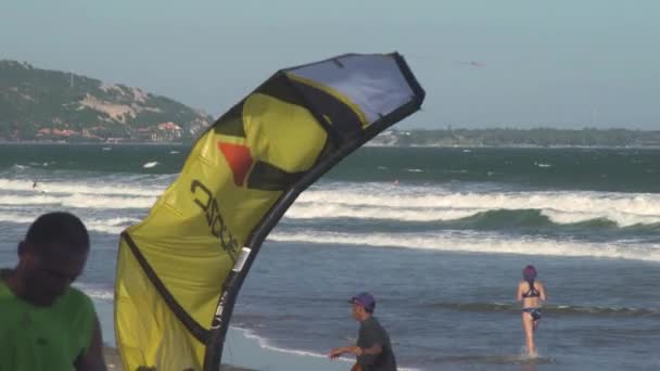 Guy πιάνει κίτρινο γκρι χαρταετό surfing στην αμμώδη παραλία του ωκεανού — Αρχείο Βίντεο