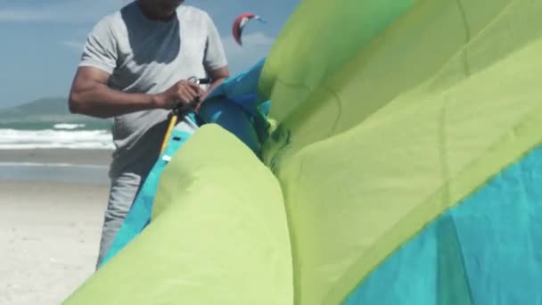 Deportista muscular fija la bomba a azul cometa verde en la playa — Vídeos de Stock