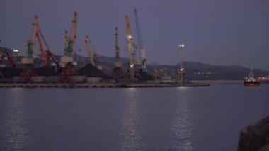 Alacakaranlıkta deniz suyuna yansıyan ışıklarla büyük iskele turnaları.