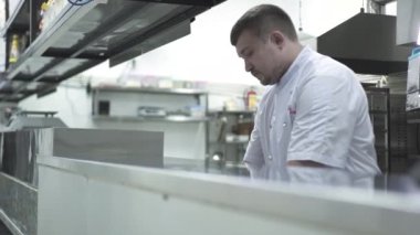 Üniformalı şef restoran mutfağında tezgahta çalışıyor.
