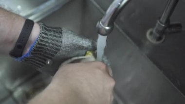 Şef deniz kabuğundan istiridyeyi su altında bıçakla alır.