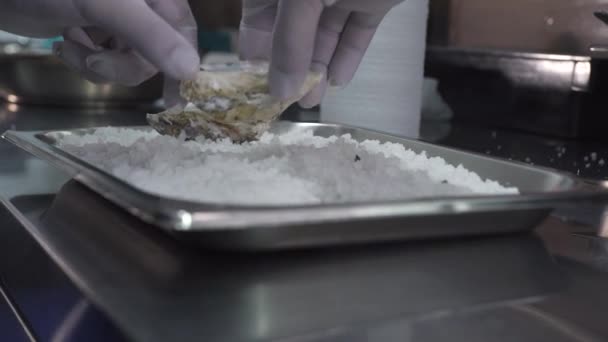 Man zet oesters op metalen dienblad met gemalen ijs in de keuken — Stockvideo