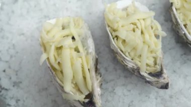 Soslu ve rendelenmiş peynirli istiridyelerin üstünde hareket