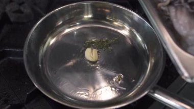 Çiğ ahtapotları tavaya sarımsak ve kekik koyarak.