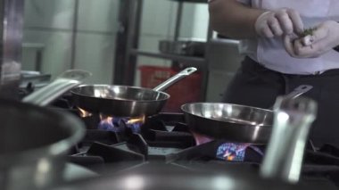 Şef yağı ısıtır ve mutfakta tavaya sarımsak koyar.