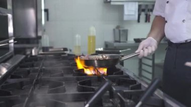 Şef mutfaktaki tavada ahtapot pişiriyor.