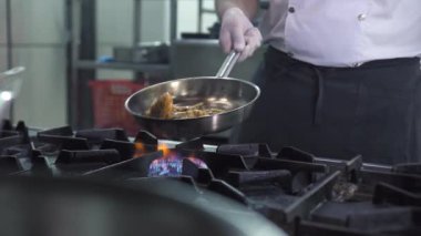 Adam mutfakta gaz ocağında karides pişiriyor.