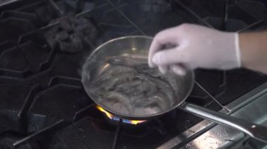 Adam deniz ürünleri restoranında tavaya kraliyet karideslerini koyar.