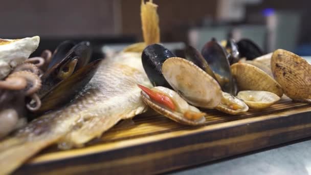 Personne met huîtres cuites au four sur pile de différentes spécialités de la mer — Video