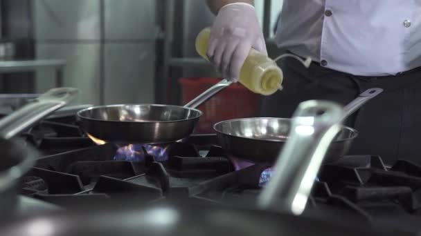 Chef derrama óleo fresco em frigideiras no fogão contemporâneo — Vídeo de Stock