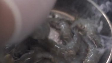 Şef tavaya çiğ karides koyar sarımsak ve kekik ile