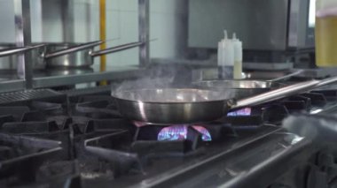 Adam yağ ekliyor ve tavayı kraliyet karidesleriyle sallıyor.