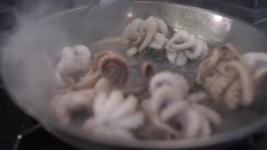 Mutfakta dilleri olan metal kızartma tavasında ahtapotları karıştırmak