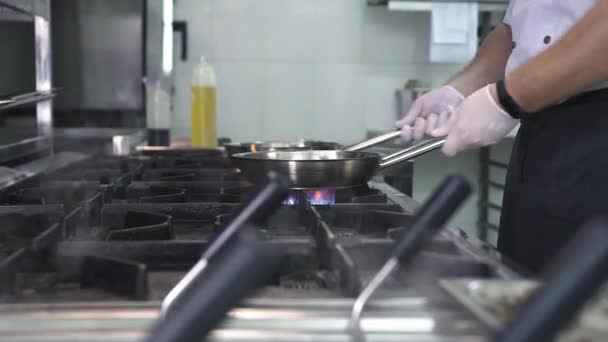 Köksarbetare pommes frites vitlök och timjan i kastruller på spisen — Stockvideo