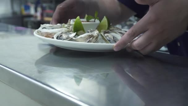 Chef gives delicious oysters to waitress in light kitchen — Stock Video