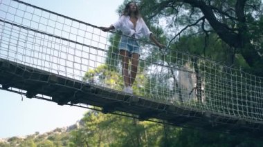 Uzun saçlı esmer, köprüde duran manzaraya hayran.