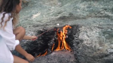 Bayan, Chimaera Dağı 'nın ateşi üzerinde lokum çubuğu tutuyor.