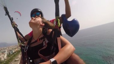 Gülen çift deniz kıyısında paraşütle uçuyor.