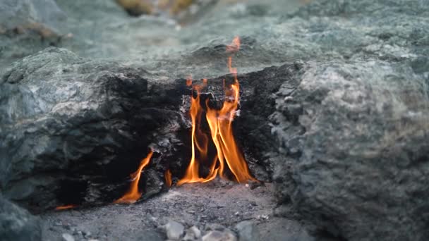 Heldere vlam brandt tussen grijze rotsen op Yanartas berg — Stockvideo