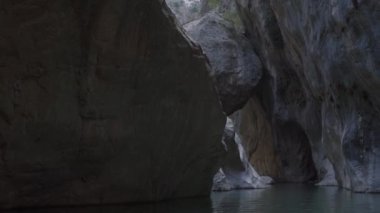 Garip şekilli büyük uçurumlar gölün üzerine karanlık gölgeler salıyor.