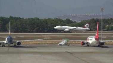 Beyaz jet yeşil ormanlara karşı asfalt piste indi