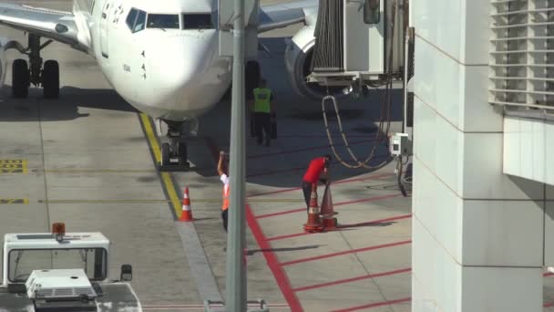 Trabajadores del aeropuerto rodean jet liner con conos de advertencia — Vídeo de stock