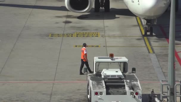 Люди в цветных комбинезонах работают рядом с белыми самолетами — стоковое видео