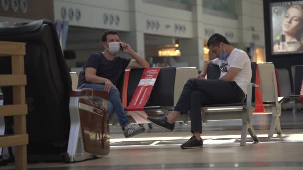 Man in disposable face mask talks on cellphone in airport — Stock Video
