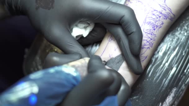 Профессиональный татуировщик окрашивает руку человека в черный цвет — стоковое видео