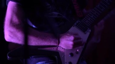 Adam konserde sahnede elektro gitar çalıyor.