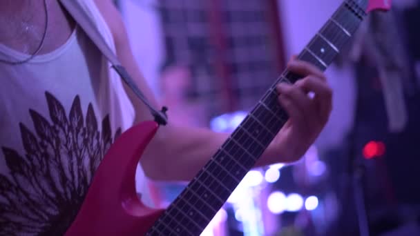 Genç adam sahnede grupla birlikte kırmızı gitar çalıyor. — Stok video