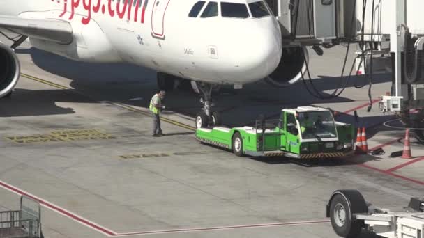 A repülőtéri munkás szabályozza a vontatójármű mozgását a kötényen — Stock videók