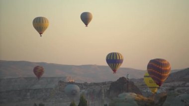 Parlak balonlar açık gökyüzüne karşı kayalık vadinin üzerinde yüzerler.