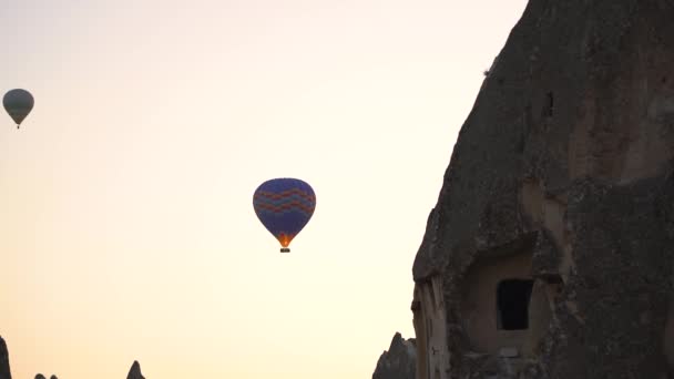 Silhueta de balão de ar quente perto da montanha com casa de caverna — Vídeo de Stock