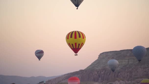 Leuchtend gelber roter Heißluftballon schwebt im Himmel über Felsen — Stockvideo