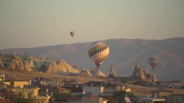 Şehrin yukarısında gökkuşağıyla süslenmiş muazzam sıcak hava balonu.