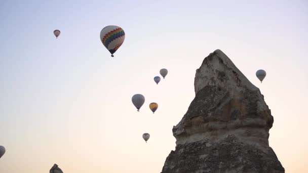 Varmluftsballonger flyter på himlen medan fåglar flyger över sten — Stockvideo