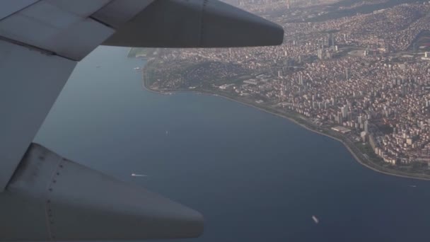 Ala grigia di aereo che vola sopra la grande città vicino al mare — Video Stock