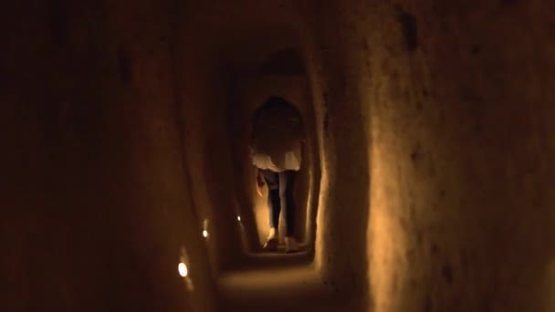 Женщина бежит по проходу с низким потолком в пещере ручной работы — стоковое видео