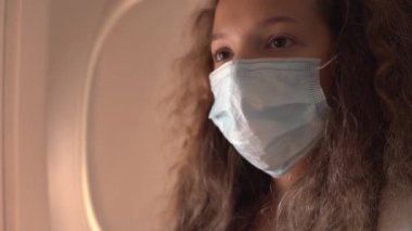 Kadın, koruyucu maskeyi uçağın kabininde otururken ayarlıyor.