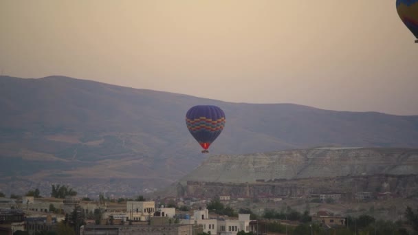 Léggömb úszik a város felett a hegy ellen napkeltekor — Stock videók