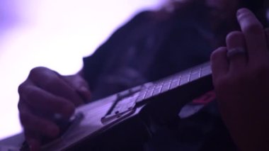 Uzun saçlı adam kulüpte modern bas gitar çalıyor.