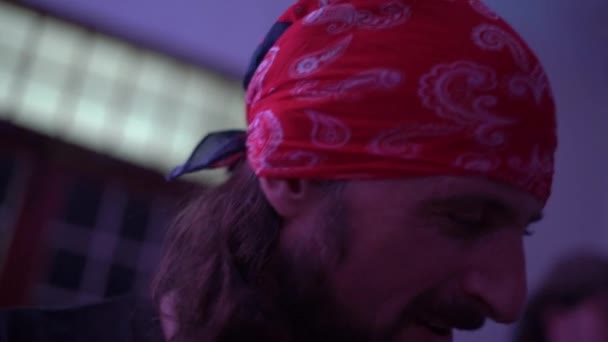 Brodaty mężczyzna z długimi włosami w bandanie gra muzykę na koncercie — Wideo stockowe