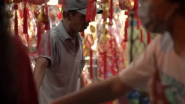 Yüzü maskeli ve şapkalı yerel halk sokak dükkanlarının önünden geçiyor