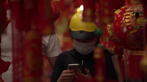 Lady in yellow helmet types on smartphone among decorations — Stock Video