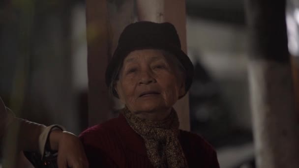 Пожилая женщина с седыми волосами под шляпой смотрит вокруг и улыбается — стоковое видео