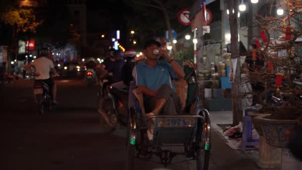 El hombre se sienta en rickshaw y bebe café de una taza pequeña — Vídeos de Stock