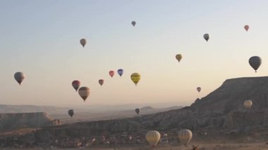 Renkli zarflı çeşitli sıcak hava balonları şafakta uçar.