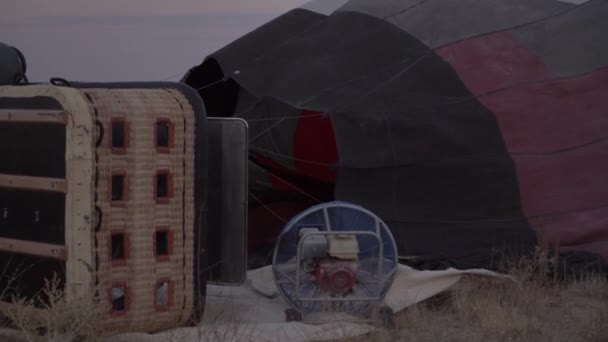 Gorące powietrze wypełnia czarną czerwoną i szarą kopertę balonu na ziemi — Wideo stockowe