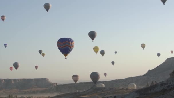 Olika färgglada varmluftsballonger flyger över berg — Stockvideo